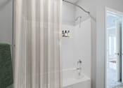 Thumbnail 9 of 15 - A white bathroom with a green towel hanging on the side.