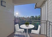 Thumbnail 11 of 15 - A balcony with a table and chairs overlooking a forest.