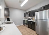 Thumbnail 3 of 15 - A modern kitchen with a stainless steel refrigerator and black cabinets.