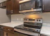 Thumbnail 10 of 24 - A modern kitchen with a stove top oven and microwave above it.