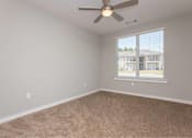 Thumbnail 14 of 24 - A room with a ceiling fan and carpeted floor.