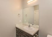 Thumbnail 18 of 24 - A bathroom with a sink, mirror, and toilet.