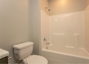 Thumbnail 19 of 24 - A white toilet sits next to a white bathtub in a bathroom.