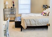 Thumbnail 7 of 24 - A bedroom with a bed, nightstand, and chair.