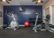 Thumbnail 18 of 27 - A home gym with a treadmill, exercise bike, and weights.
