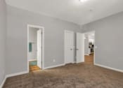 Thumbnail 4 of 27 - A room with carpeted floor and white walls with two doors.