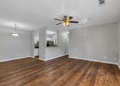 Thumbnail 3 of 27 - A room with a ceiling fan and wooden flooring.