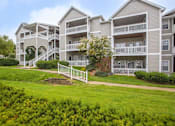 Thumbnail 27 of 27 - Apartment complex with green grass and white fence.