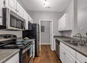 Thumbnail 2 of 27 - A kitchen with black appliances and white cabinets.