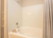 Thumbnail 11 of 27 - A white bathtub with a shower curtain and a shower head.