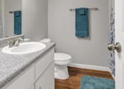Thumbnail 5 of 27 - A bathroom with a white toilet and a white sink with a granite counter top.