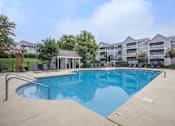 Thumbnail 21 of 27 - A swimming pool in front of a building with a gazebo.