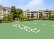 Thumbnail 24 of 27 - A green tennis court in front of apartment buildings.