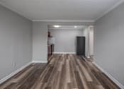 Thumbnail 9 of 31 - A room with wooden flooring and a black refrigerator.