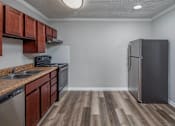 Thumbnail 8 of 31 - A kitchen with a black fridge and brown cabinets.