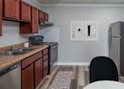 Thumbnail 30 of 31 - A kitchen with brown cabinets and a black chair.