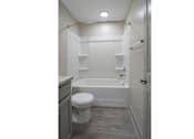 Thumbnail 6 of 31 - A white toilet sits next to a bathtub in a small bathroom.