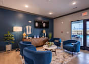 Thumbnail 1 of 38 - A waiting room with blue chairs and a flat screen TV.