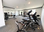 Thumbnail 4 of 38 - A spacious gym with a variety of equipment including treadmills, stationary bikes, and weight machines.