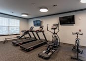 Thumbnail 6 of 38 - A gym with treadmills, exercise bikes, and a television.