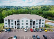 Thumbnail 15 of 15 - A large light grey building with a parking lot in front of it.