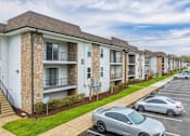 Thumbnail 10 of 25 - A row of apartment buildings with cars parked in front.