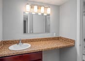 Thumbnail 17 of 25 - A bathroom sink with a granite countertop and a mirror above it.