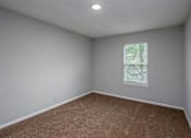Thumbnail 21 of 25 - A room with a carpeted floor and a window with blinds.