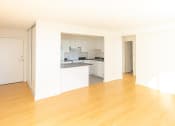 Thumbnail 3 of 7 - an empty living room with a kitchen in the background