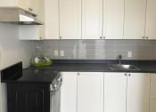 Thumbnail 5 of 7 - a kitchen with white cabinets and a black counter top