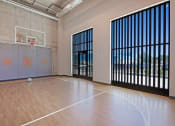 Thumbnail 29 of 74 - an empty gym with a basketball hoop and wood flooring