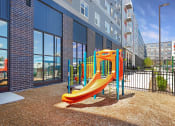 Thumbnail 48 of 74 - a playground at a building with a yellow slide