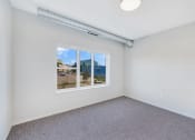 Thumbnail 26 of 74 - a bedroom with a window and a carpeted floor