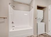 Thumbnail 14 of 74 - a white bathroom with a shower and a washer and dryer in it