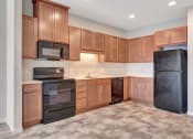 Thumbnail 9 of 74 - an empty kitchen with wood cabinets and black appliances