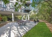 Thumbnail 37 of 61 - a patio with a grill and picnic tables in front of a building