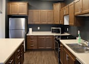 Thumbnail 11 of 21 - A kitchen with wooden cabinets and a stainless steel refrigerator.