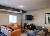 Thumbnail 12 of 21 - A living room with a brown couch, a grey armchair, and a coffee table.