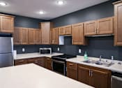 Thumbnail 6 of 21 - A kitchen with wooden cabinets and a white countertop.