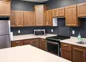 Thumbnail 20 of 21 - A kitchen with wooden cabinets and a white countertop.