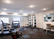 Thumbnail 3 of 21 - A gym with a variety of equipment including weights and cardio machines.