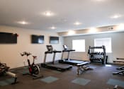 Thumbnail 9 of 21 - A gym with a variety of equipment including treadmills, stationary bikes, and weight racks.