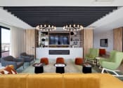 Thumbnail 17 of 24 - Platform community lounge room with a yellow couch and chairs and a fireplace with a television at Platform 4611, Chicago, IL 60640