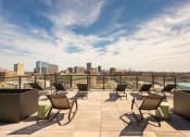 Thumbnail 15 of 24 - an outdoor terrace with lounge chairs and a pool with a city skyline in the background at Platform 4611, Illinois, 60640