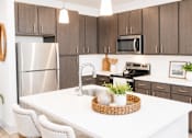 Thumbnail 14 of 22 - A kitchen with a white table and brown cabinets.