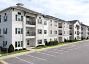 Thumbnail 23 of 28 - Apartment building with a parking lot in front.