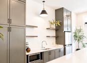 Thumbnail 10 of 22 - A modern kitchen with a white countertop and grey cabinets.