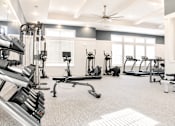 Thumbnail 7 of 22 - A gym with a variety of equipment including a treadmill, weights, and a bench press.