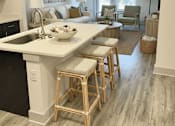 Thumbnail 11 of 28 - A kitchen with a white countertop and wooden bar stools.