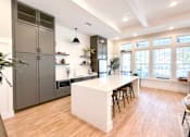 Thumbnail 14 of 28 - A kitchen with a white island and wooden floors.